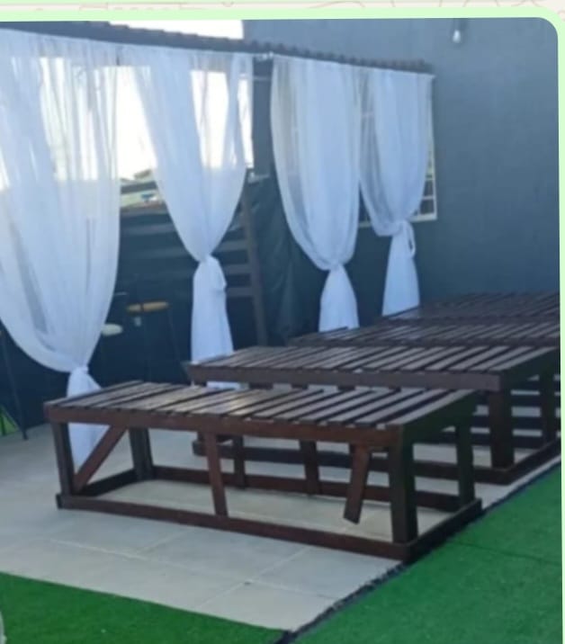 Espaço Bronze SPA Brasília — espreguiçadeiras de madeira com cortinas brancas
